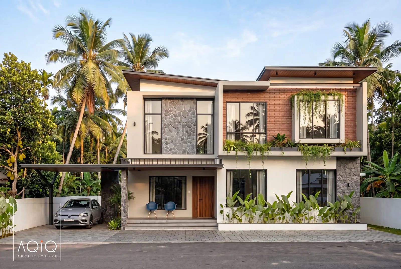 Two-storey house with stone, brick and white plaster among tropical planting
